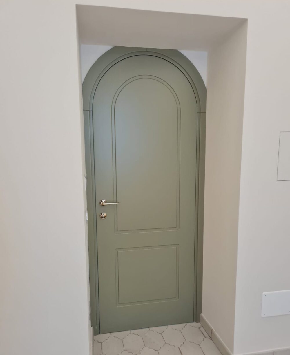 Porta ad arco laccata verde salvia su pavimento in esagonette bianche