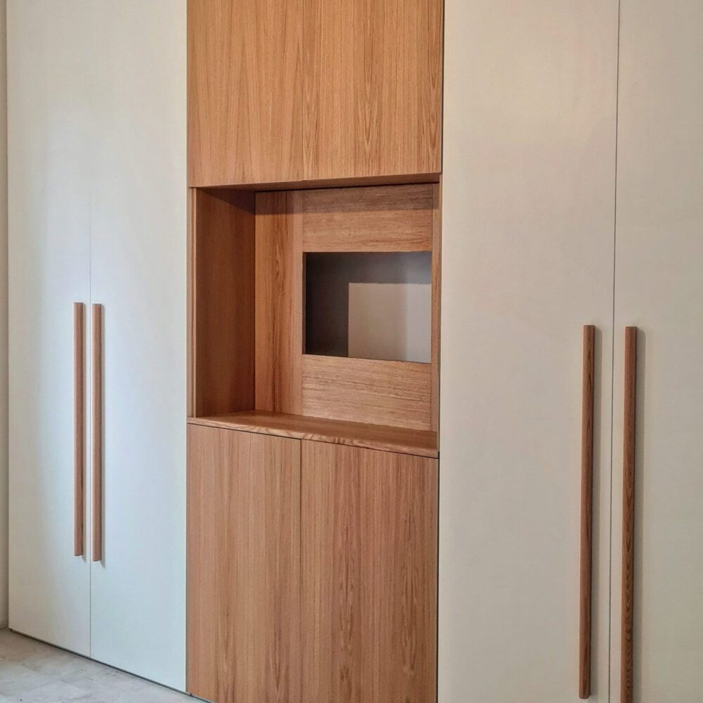 Armadio a muro bianco con vano a giorno in rovere e maniglie lunghe in legno