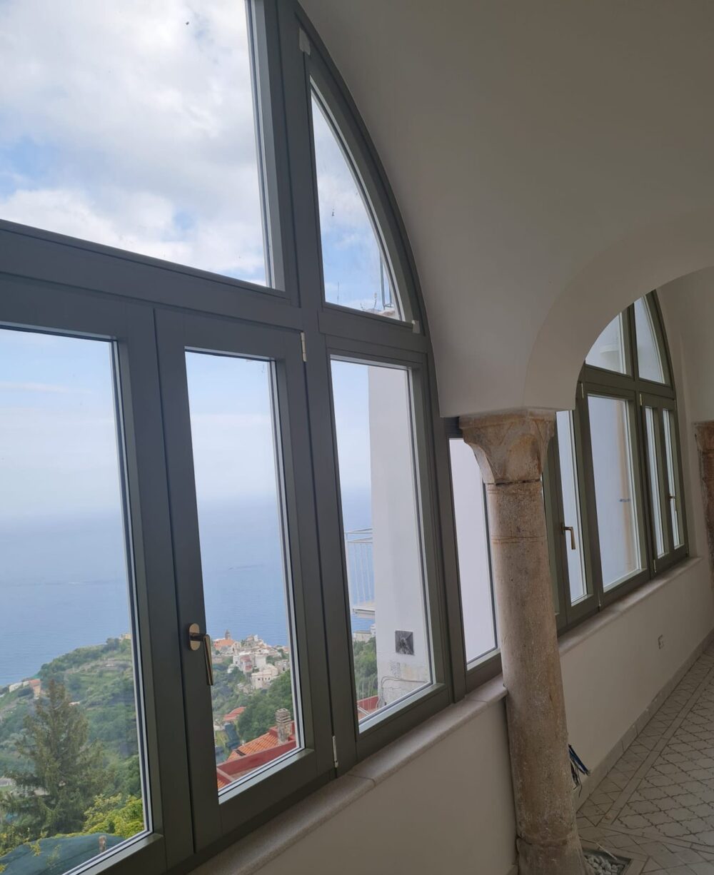 Infissi in legno verde con grande finestra ad arco affacciata sul mare