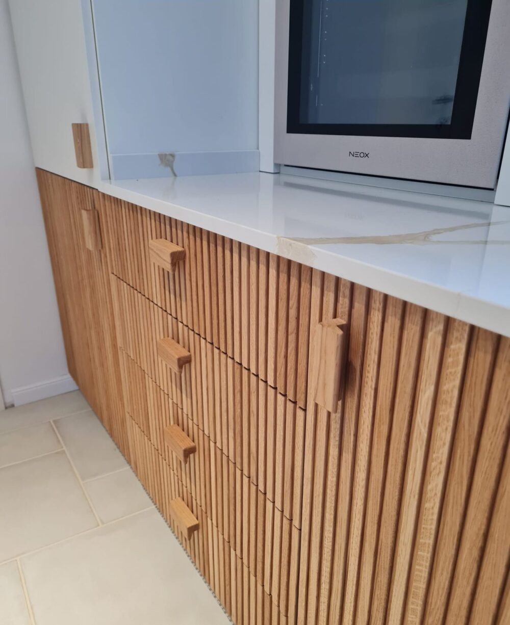 Cassettiera di cucina in rovere a listelli con maniglie in legno e piano in marmo bianco