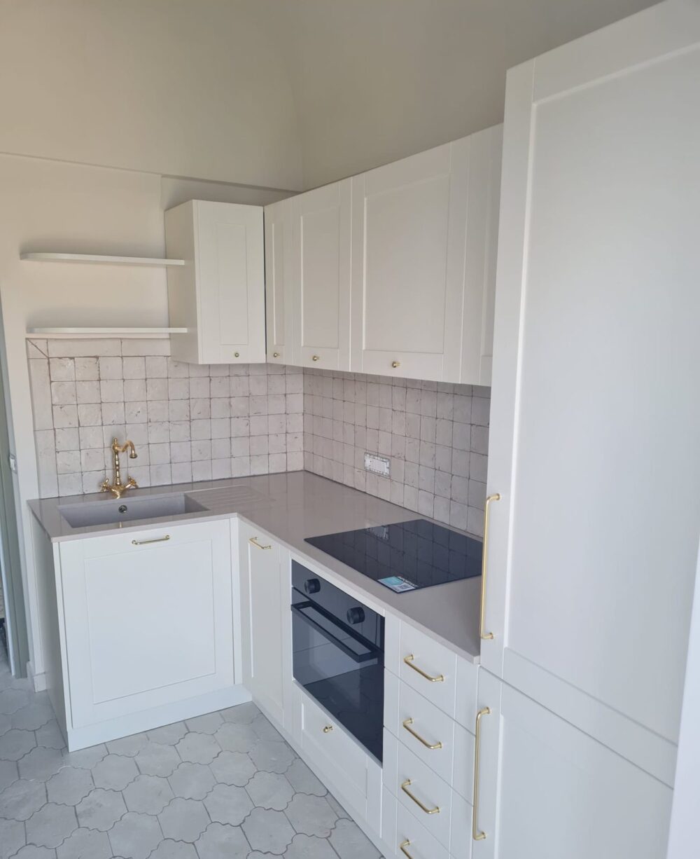Cucina bianca ad angolo con colonne a telaio, forno incassato e pavimento in esagonette
