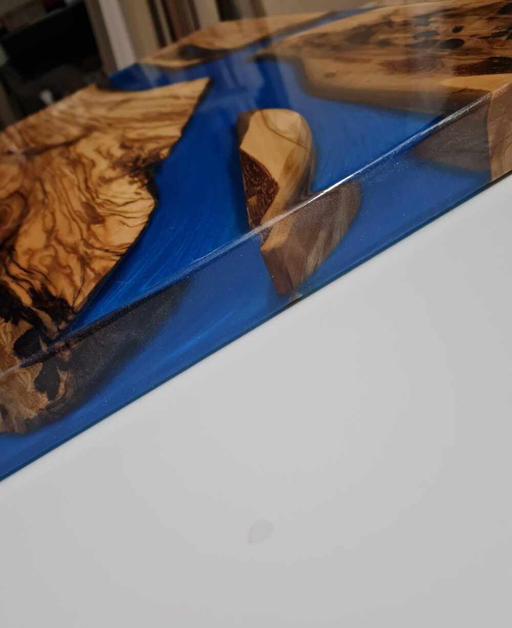 Dettaglio di piano in legno d'ulivo con resina blu su base bianca
